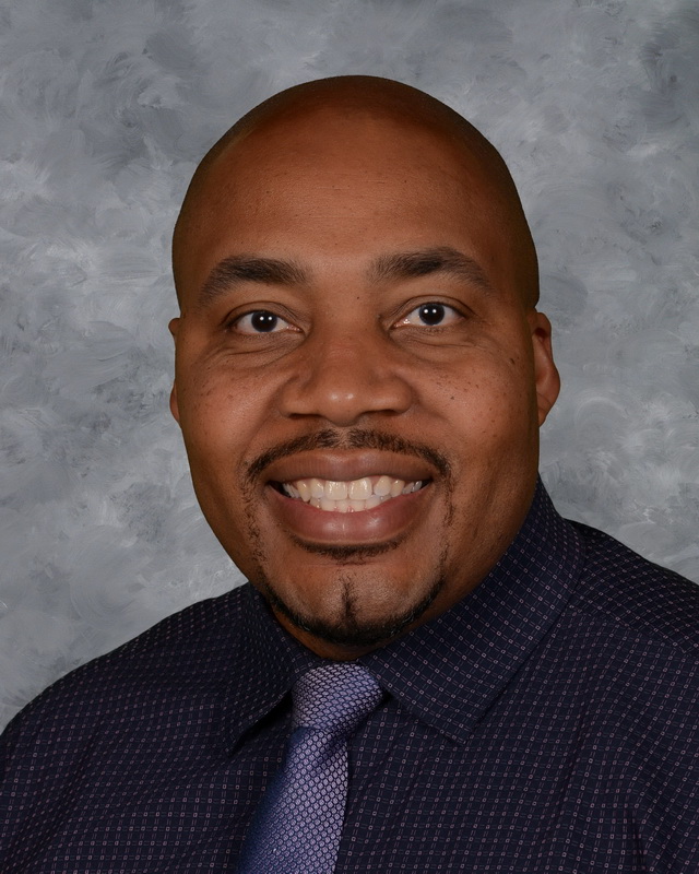Black man in a black shirt and purple tie