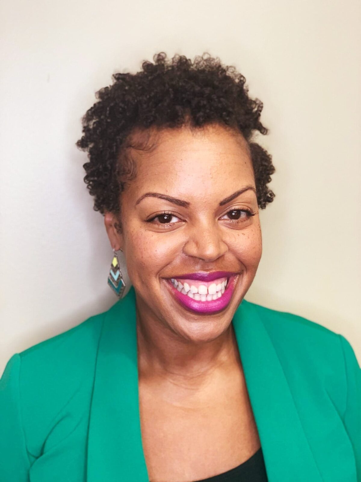Black woman wearing a green suit jacket and black shirt.