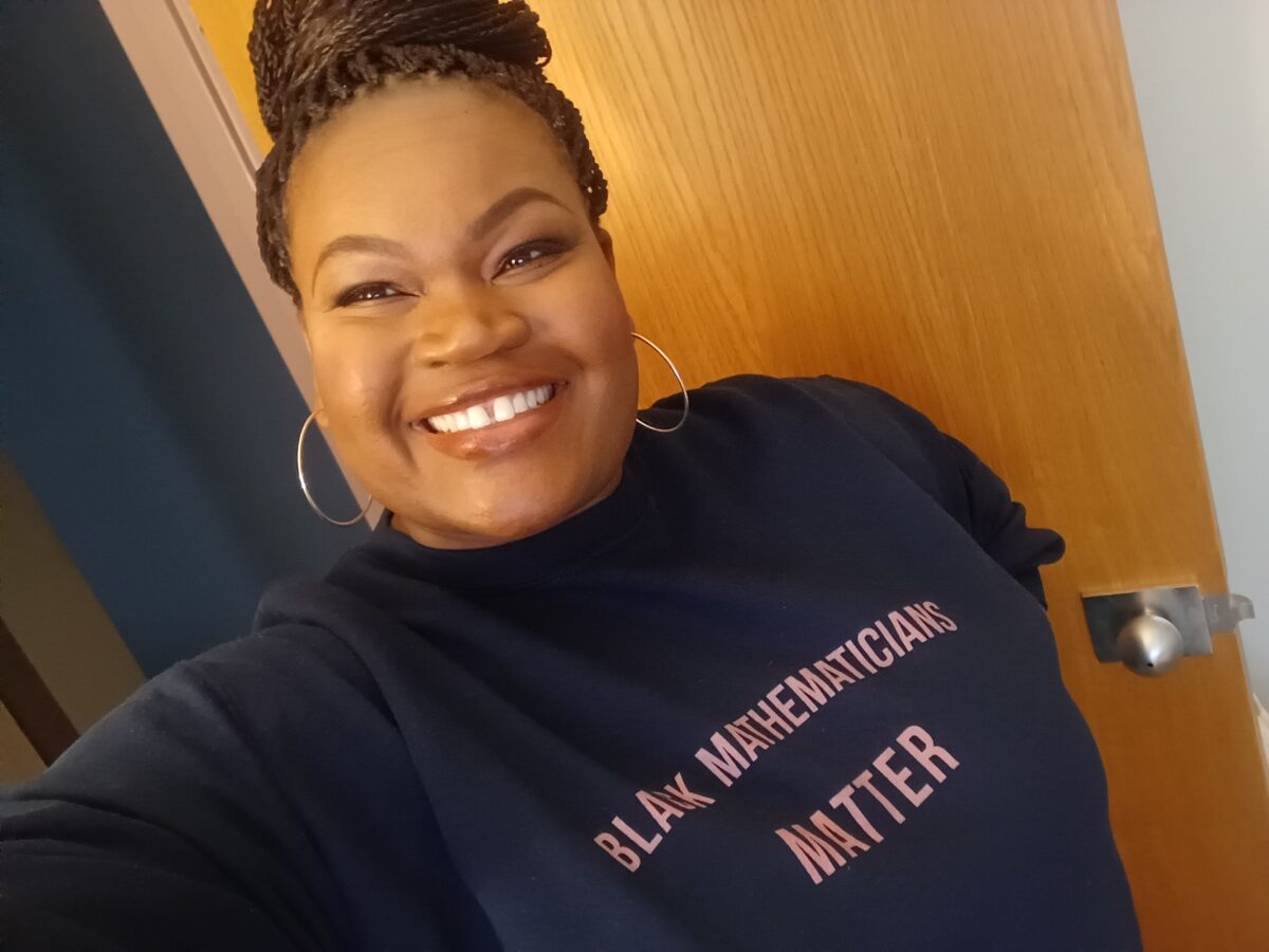 Black woman wearing a dark blue sweatshirt with the words 